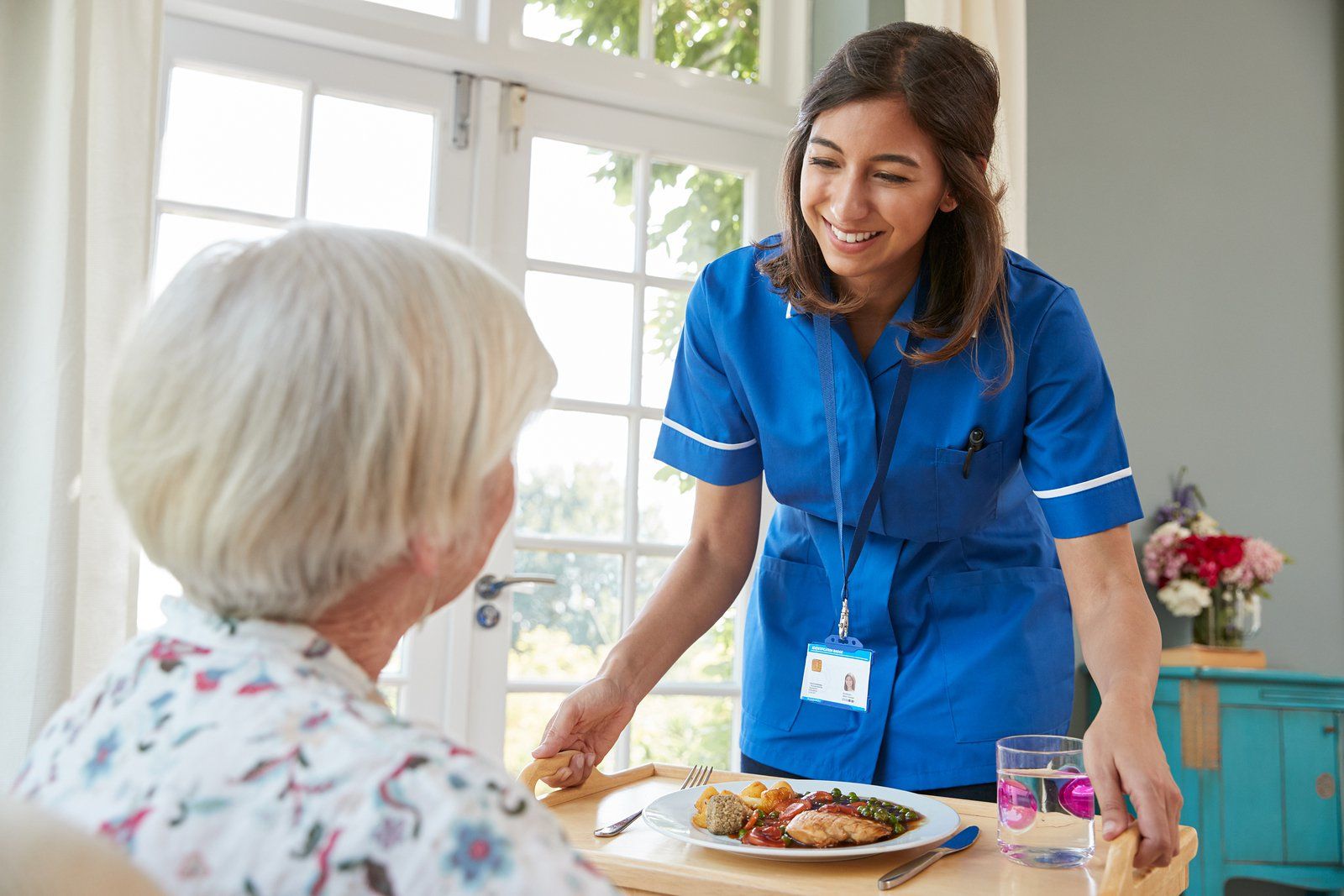 care-nurse-serving-dinner-to-a-senior-woman-at-home-cna-classes-near-you